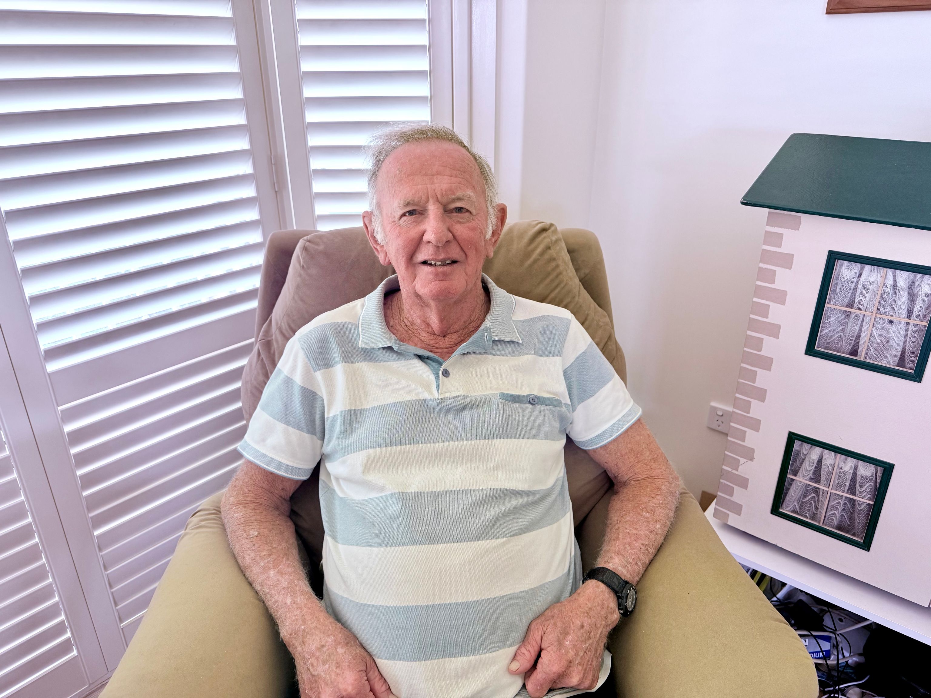Robert, a 76-year-old man, sits on an armchair in his home.