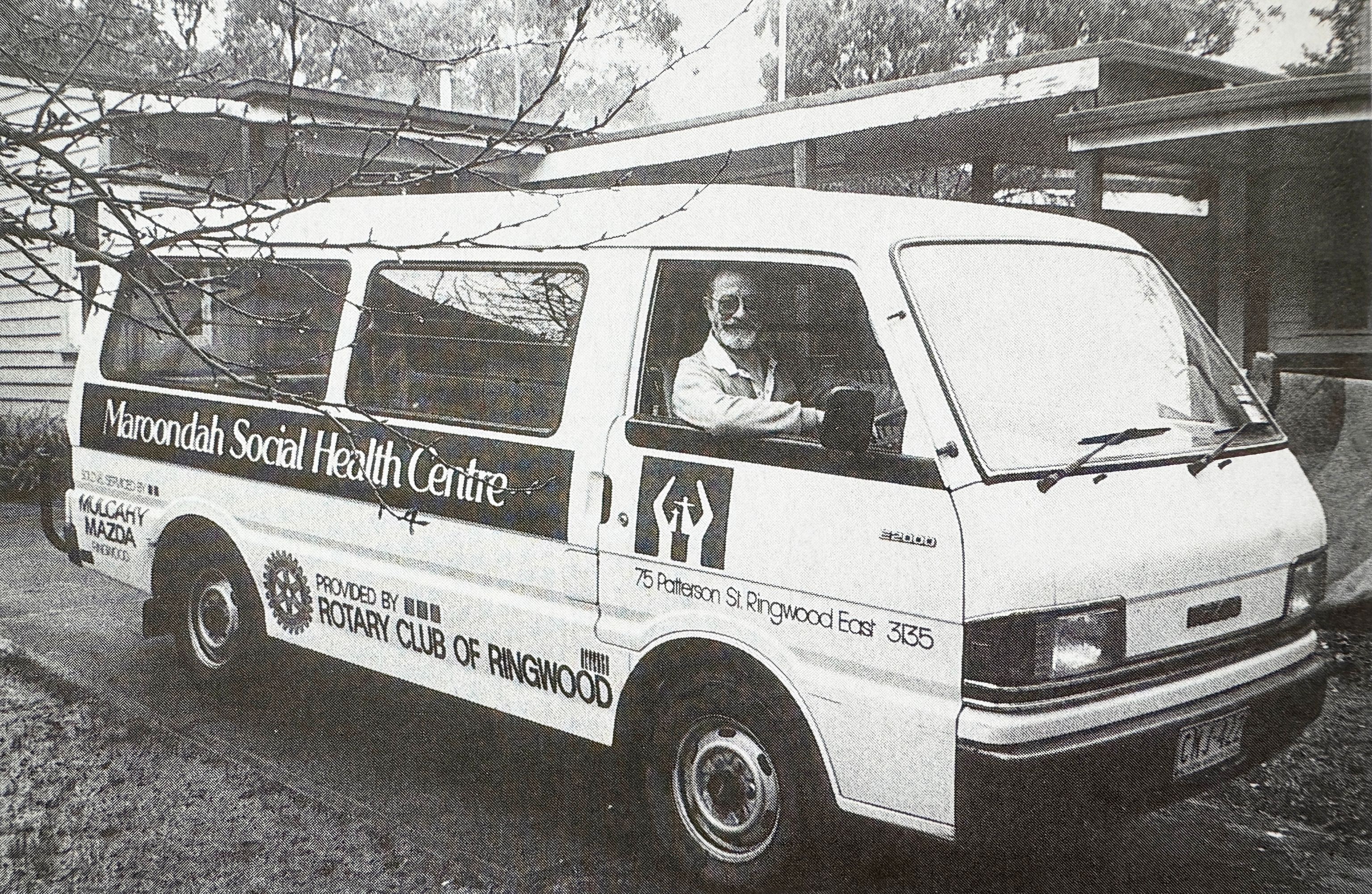 Black and white archival photograph of a man driving a social health centre van