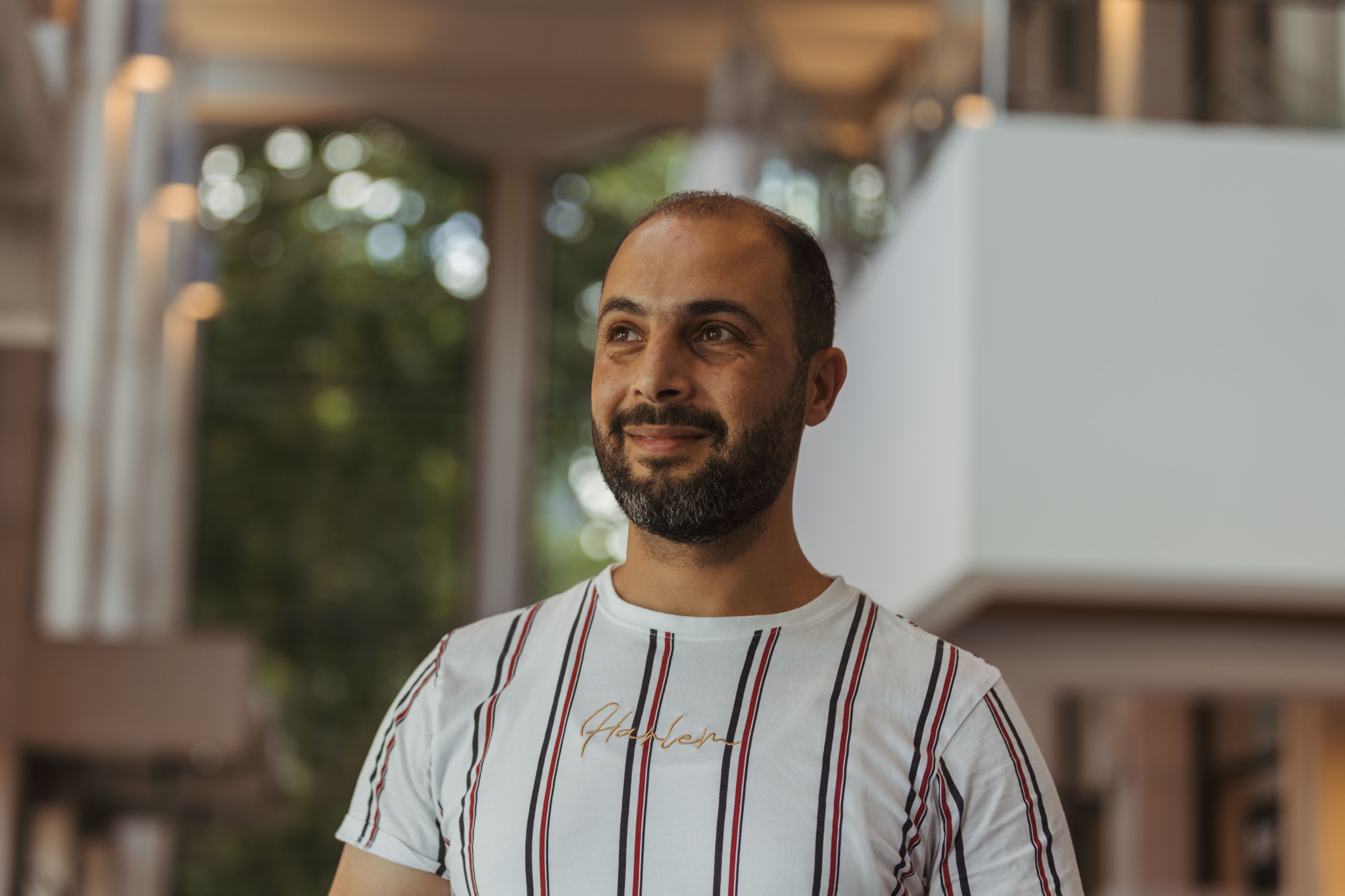 Young man standing indoors in a centre smiling and staring into the distance