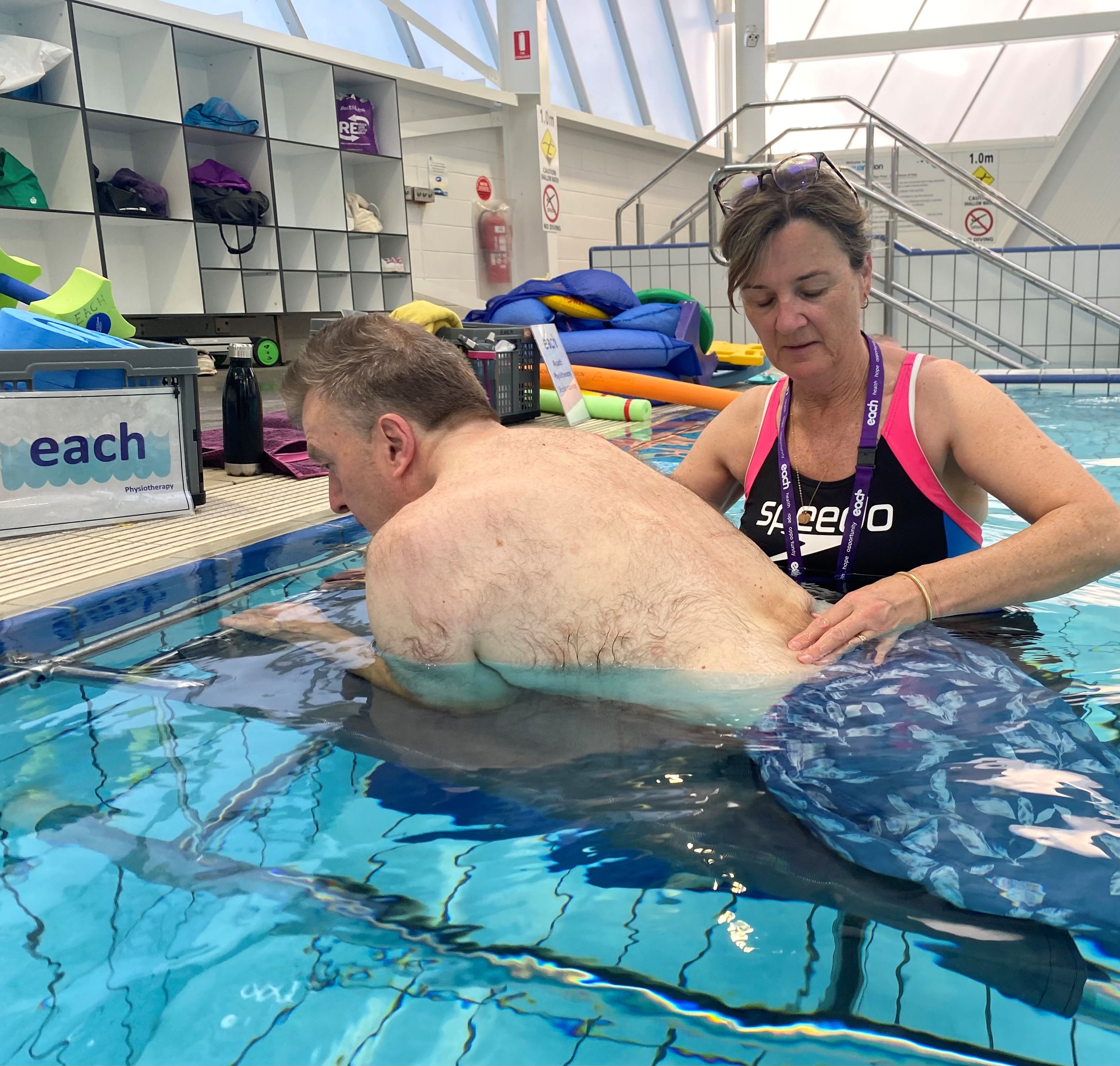 Physiotherapist Gabrielle is in a pool providing support to a man's back.