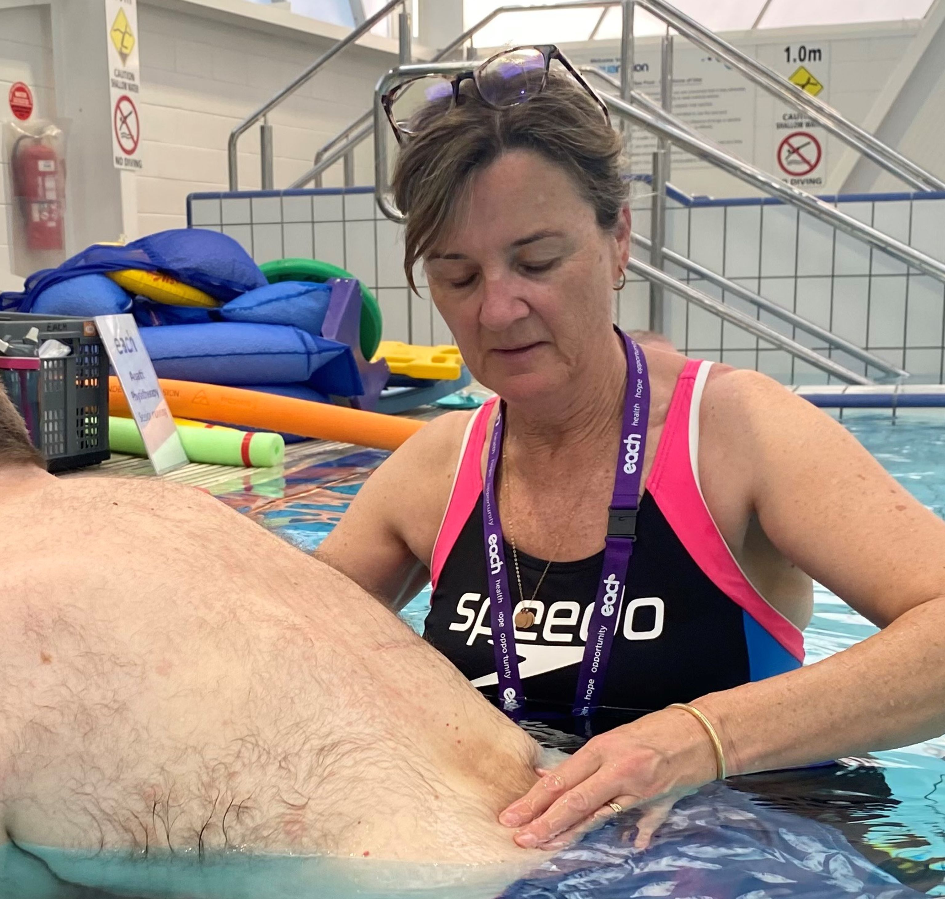 Physiotherapist Gabrielle is in a pool providing support to a man's back.