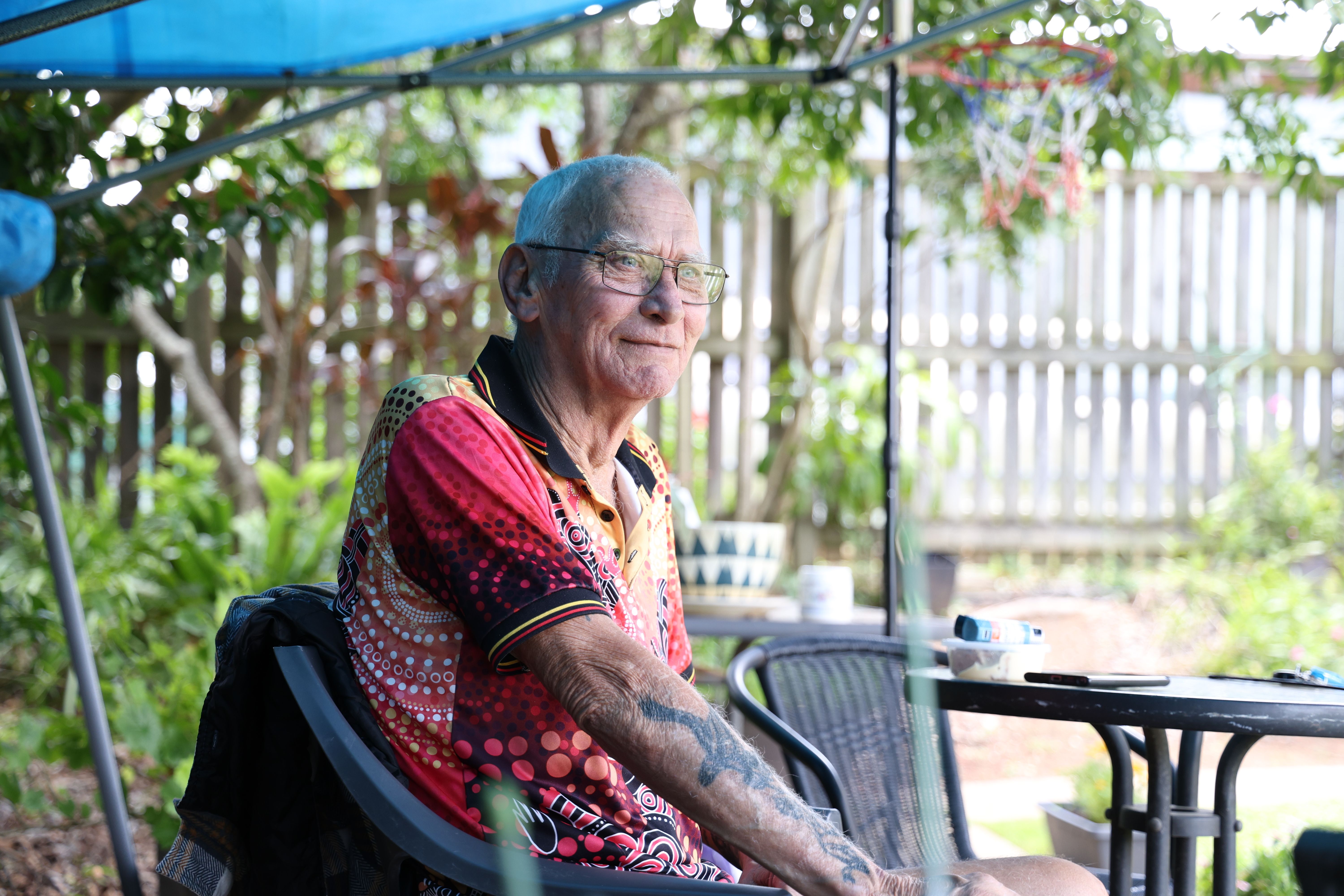 Senior man from the First Nations community sitting at an outside table and looking into the distance