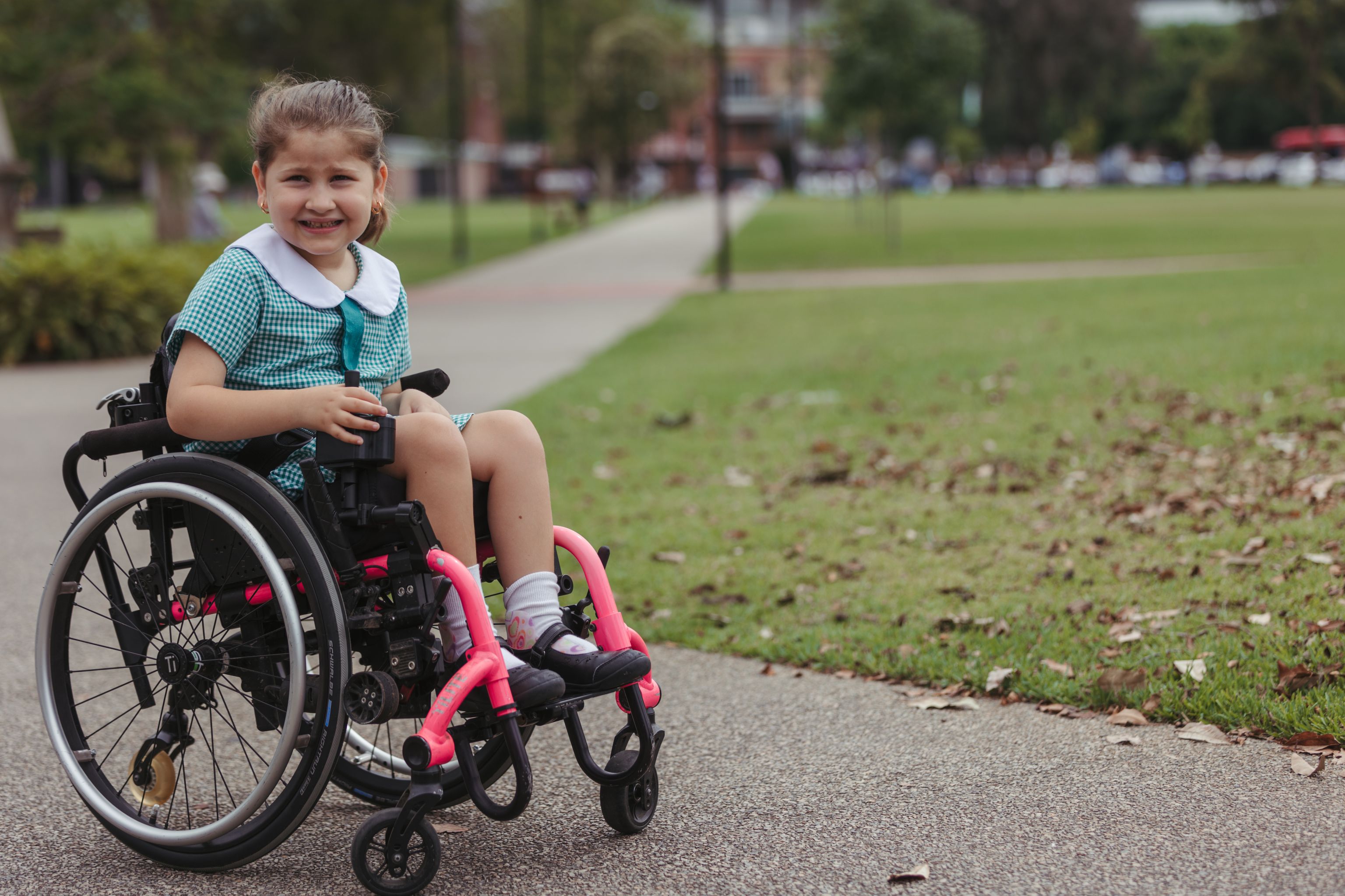 Young girl sitting in a wheelchair in a park