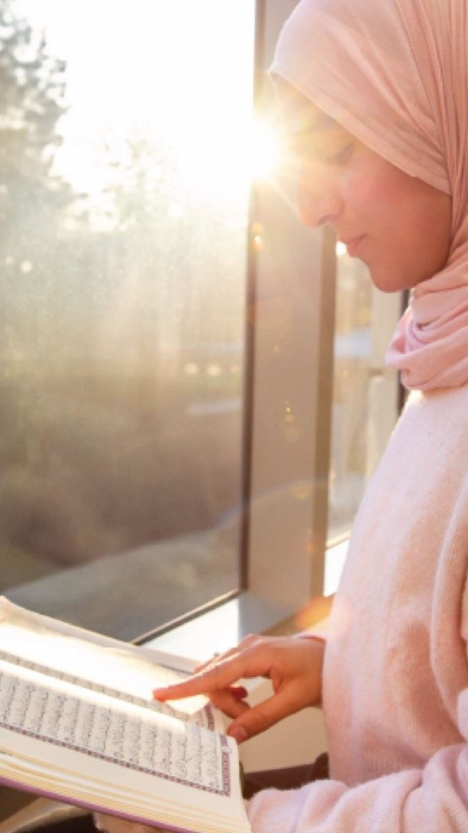A student reading the Qur'an by a window