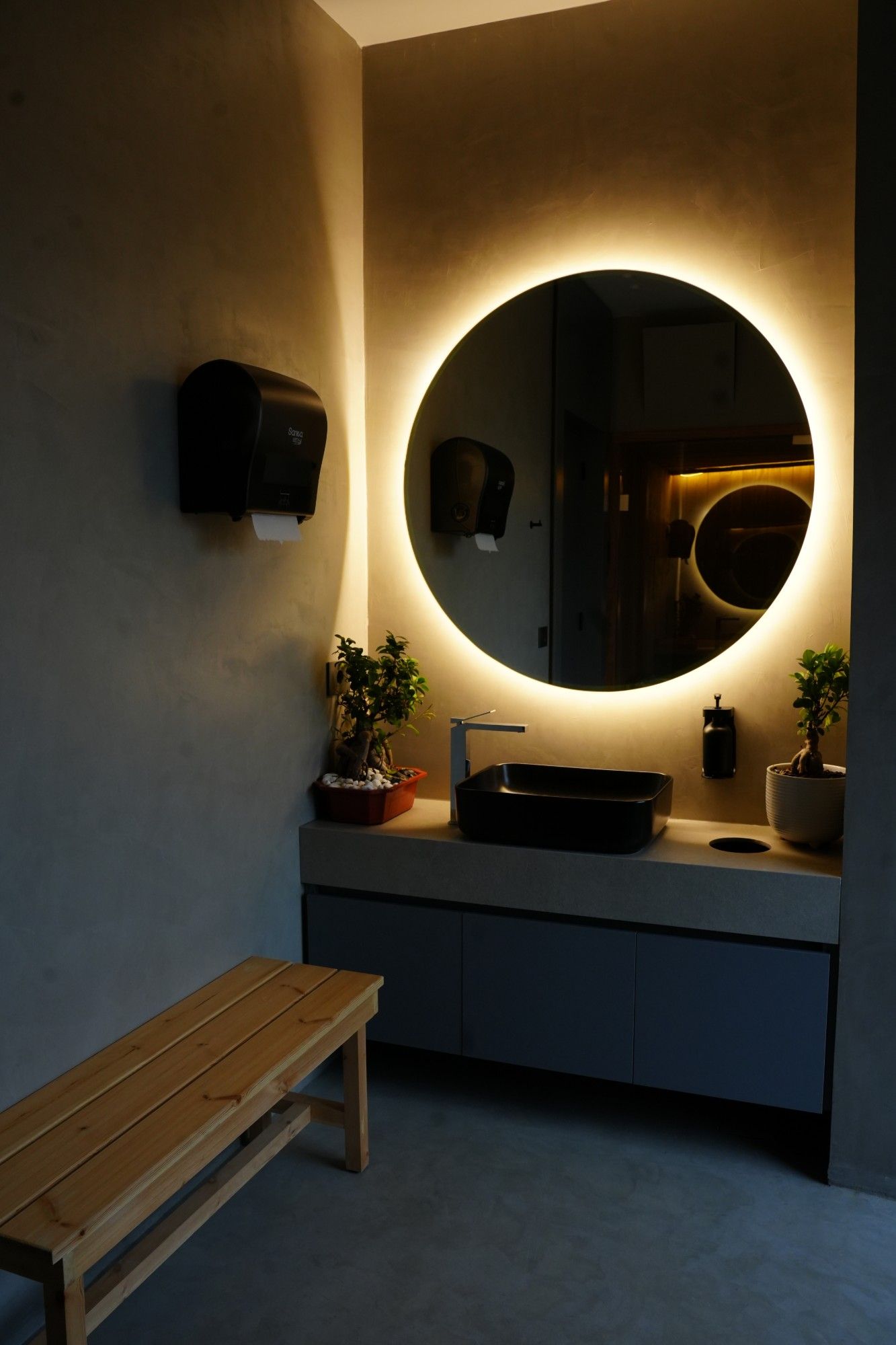 Vanity with a backlit round mirror in the locker room
