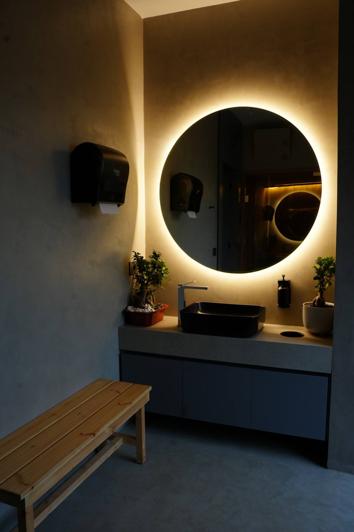 Vanity with a backlit round mirror in the locker room