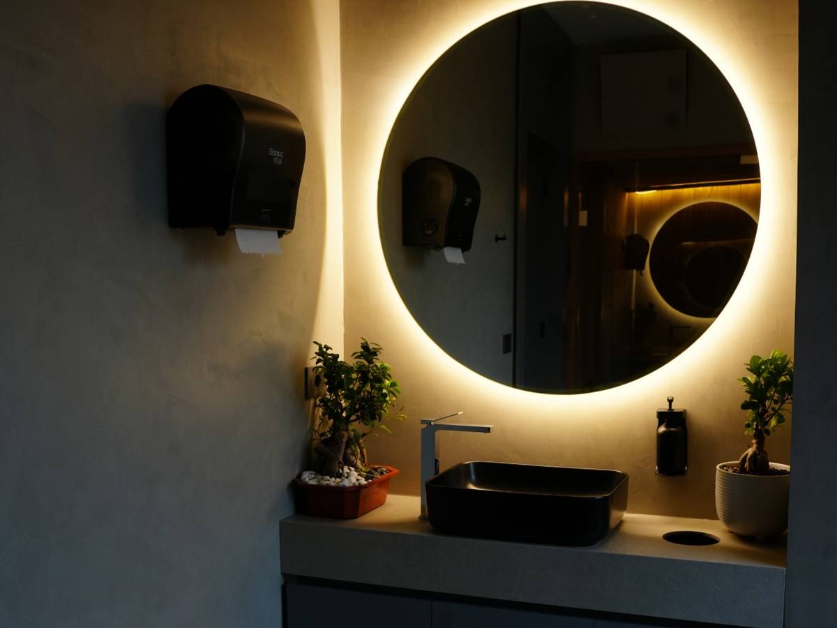 Vanity with a backlit round mirror in the locker room