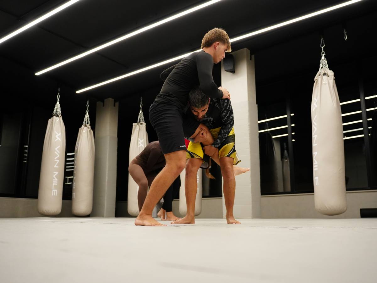 Wrestling drill on the Mat Arena, VAN MILE heavy bags behind