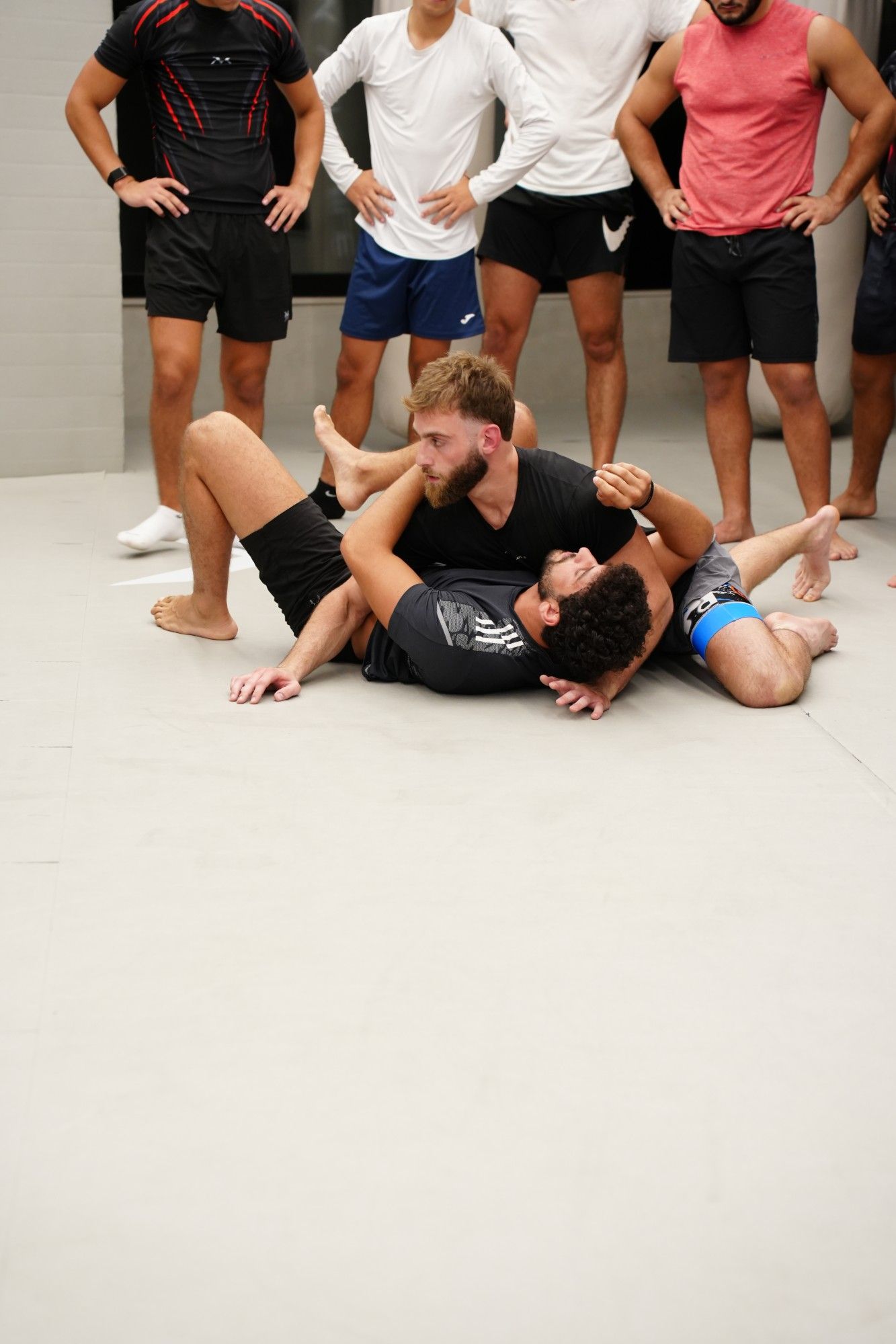 No-Gi Jiu-Jitsu technique on the mats while the class watches