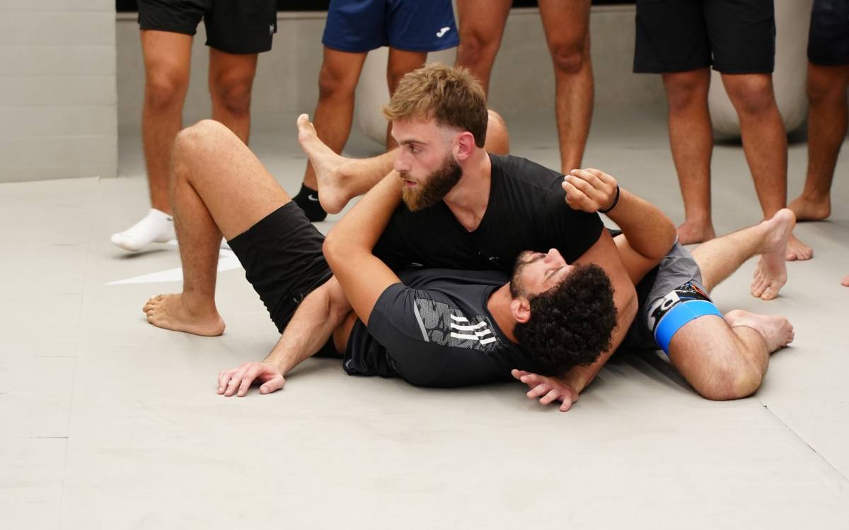No-Gi Jiu-Jitsu technique on the mats while the class watches