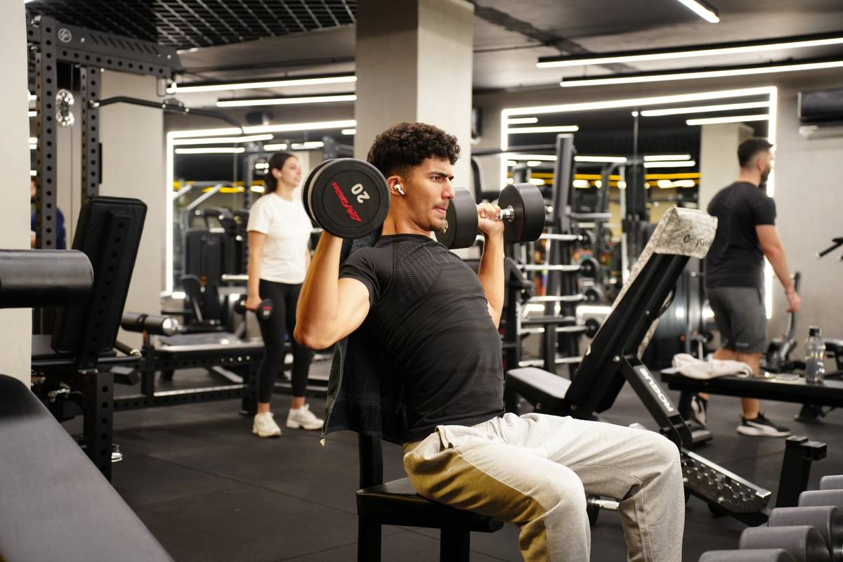 Member doing a seated dumbbell shoulder press on the gym floor