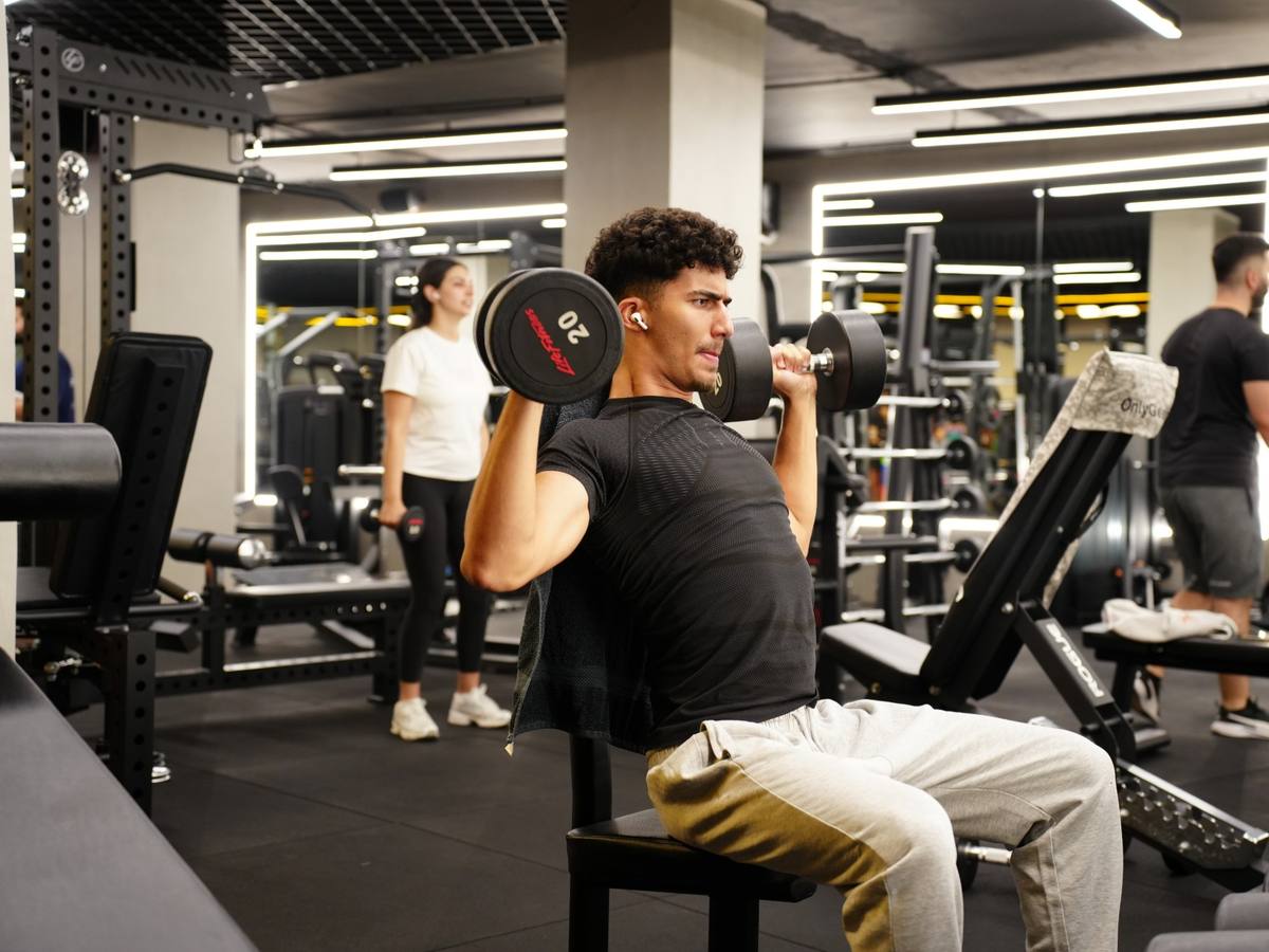 Member doing a seated dumbbell shoulder press on the gym floor