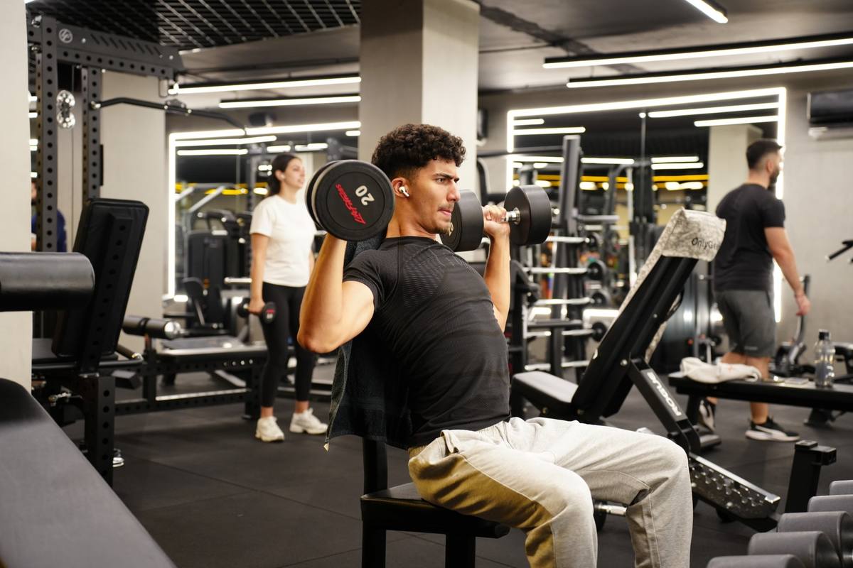 Member doing a seated dumbbell shoulder press on the gym floor