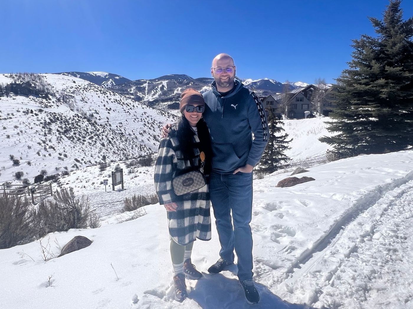 Jaury and Tyler on a snowy trail above Avon with ski slopes behind them