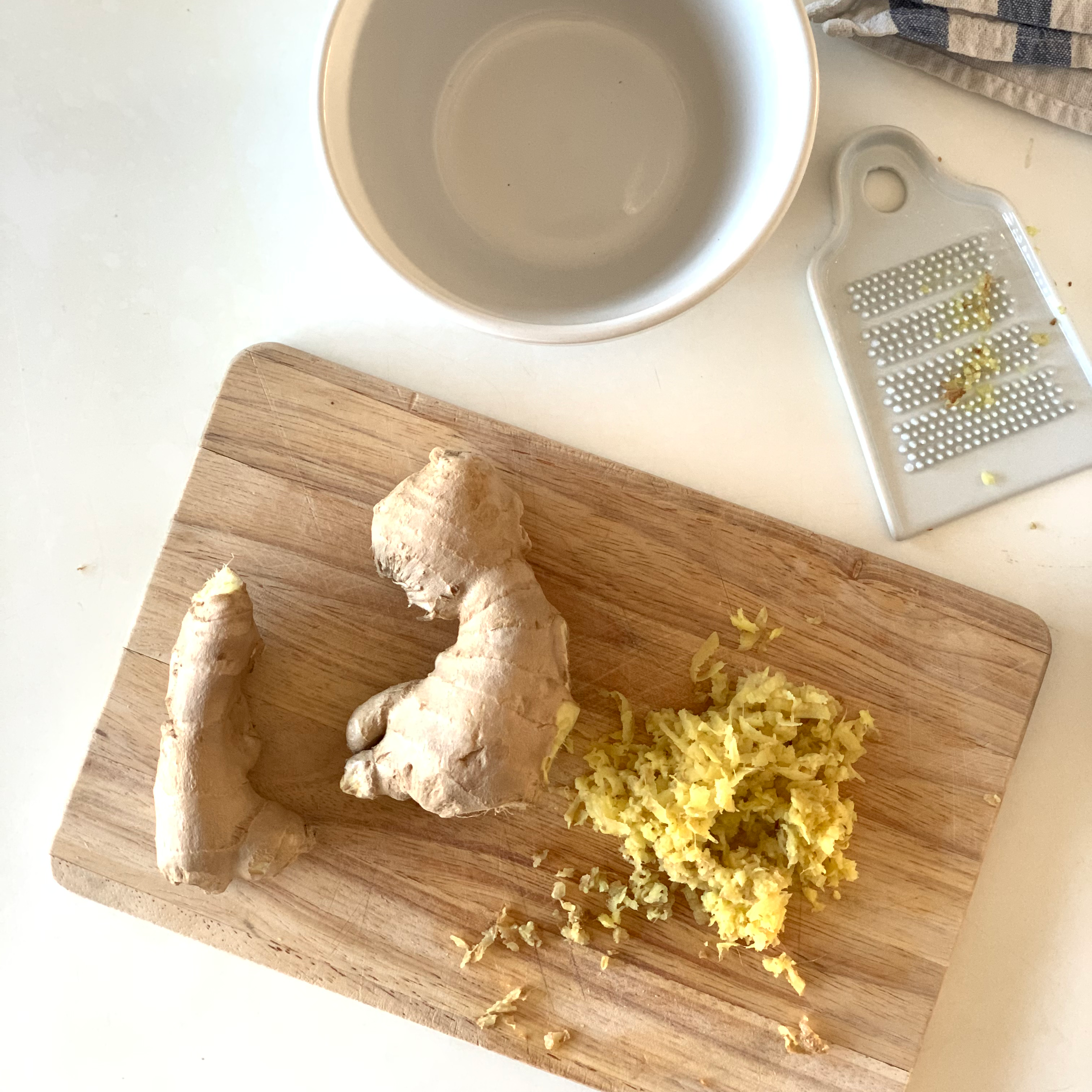ginger is being grated on a wooden cutting board
