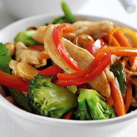 a white bowl filled with chicken , broccoli , carrots and peppers .