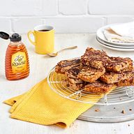 Rowse honey bottle, yellow coffee mug, and chocolate-drizzled oat bars on a wire rack.