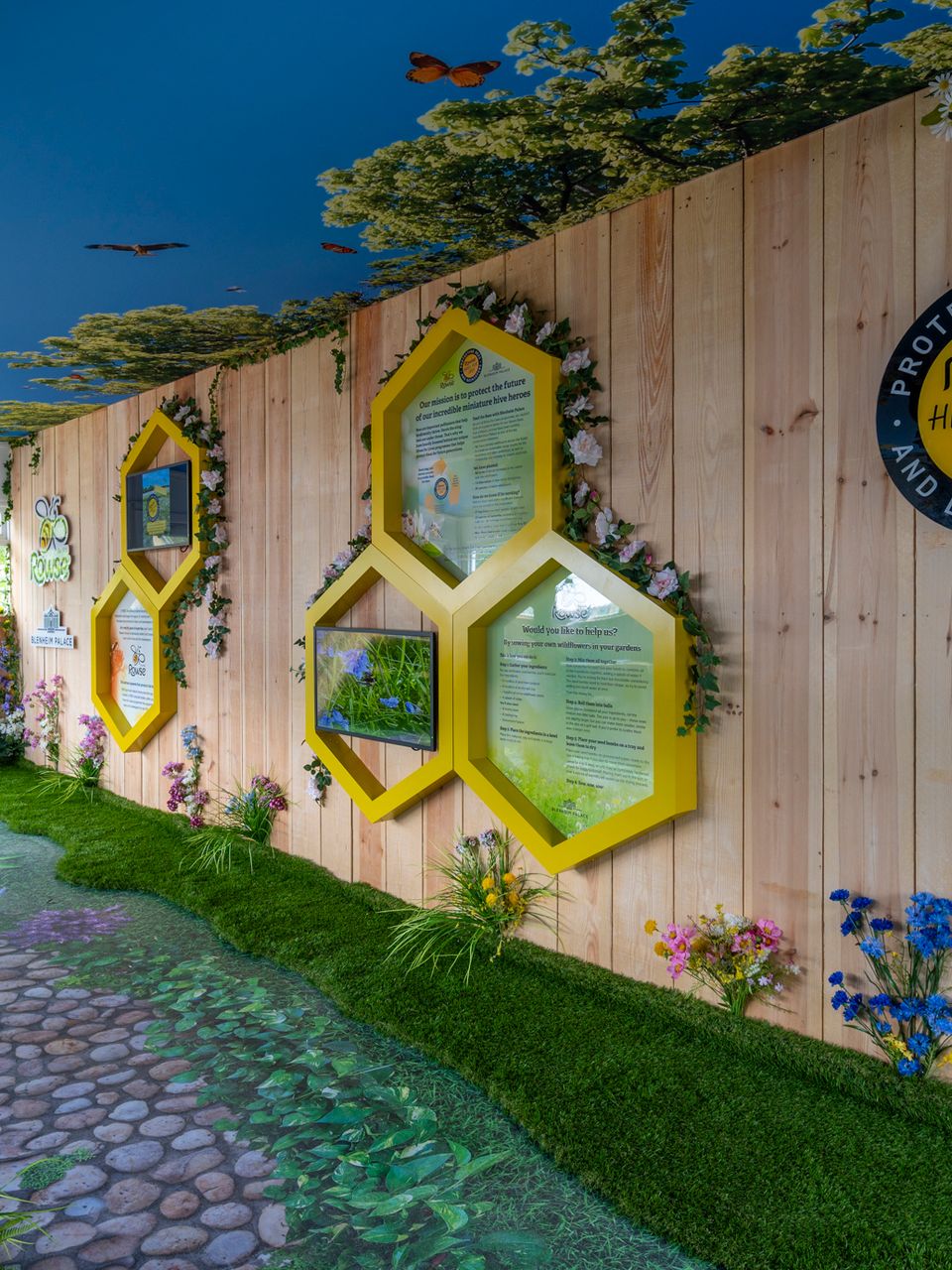 a wooden fence with beehives and flowers on it .
