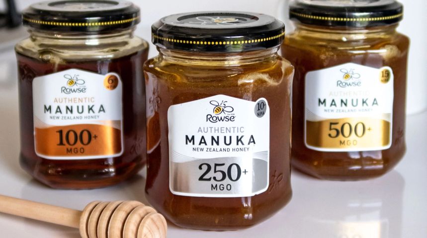 three jars of manuka honey are sitting next to each other on a table .