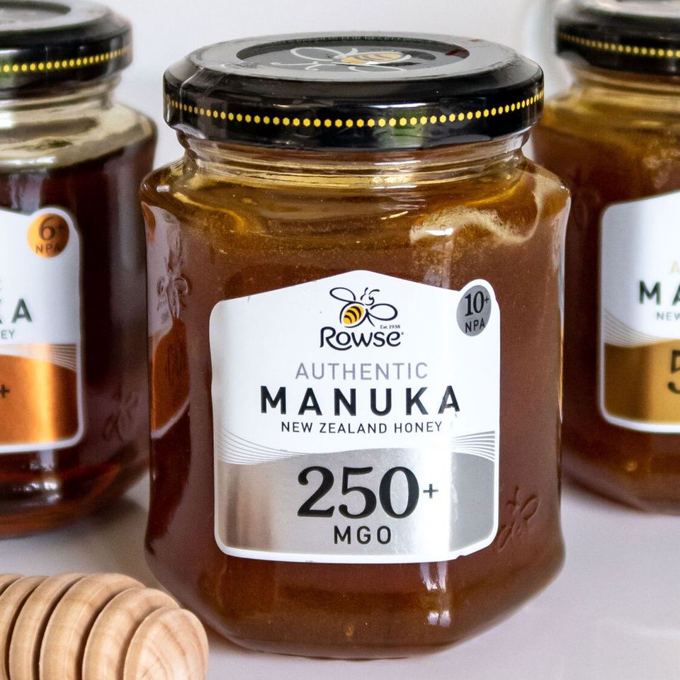 three jars of manuka honey are sitting next to each other on a table .
