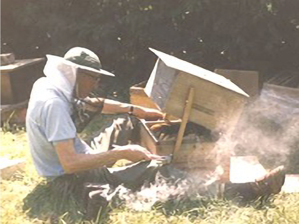 a man wearing a hat is working on a beehive