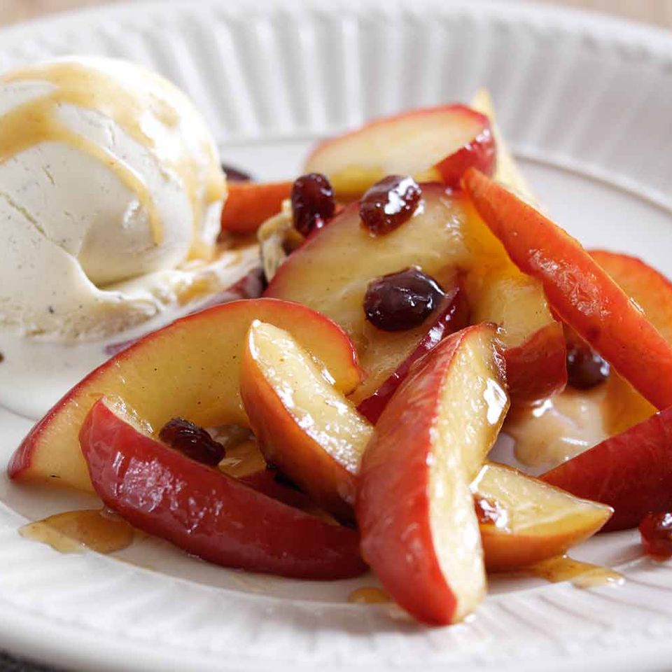 a white plate topped with apples , cranberries and ice cream .
