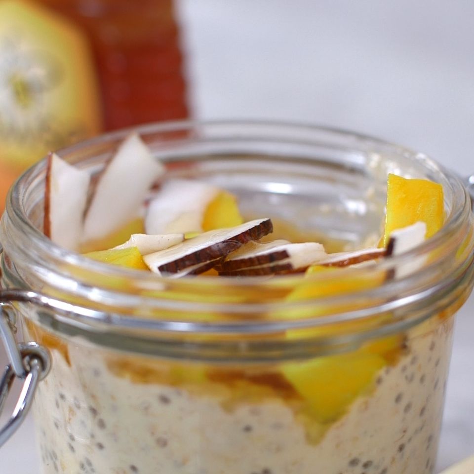a jar filled with oatmeal , fruit , coconut and honey .