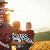 a man is carrying two children on his shoulders in a field .