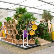 a woman is walking through a tent with a display of honeycombs and plants .