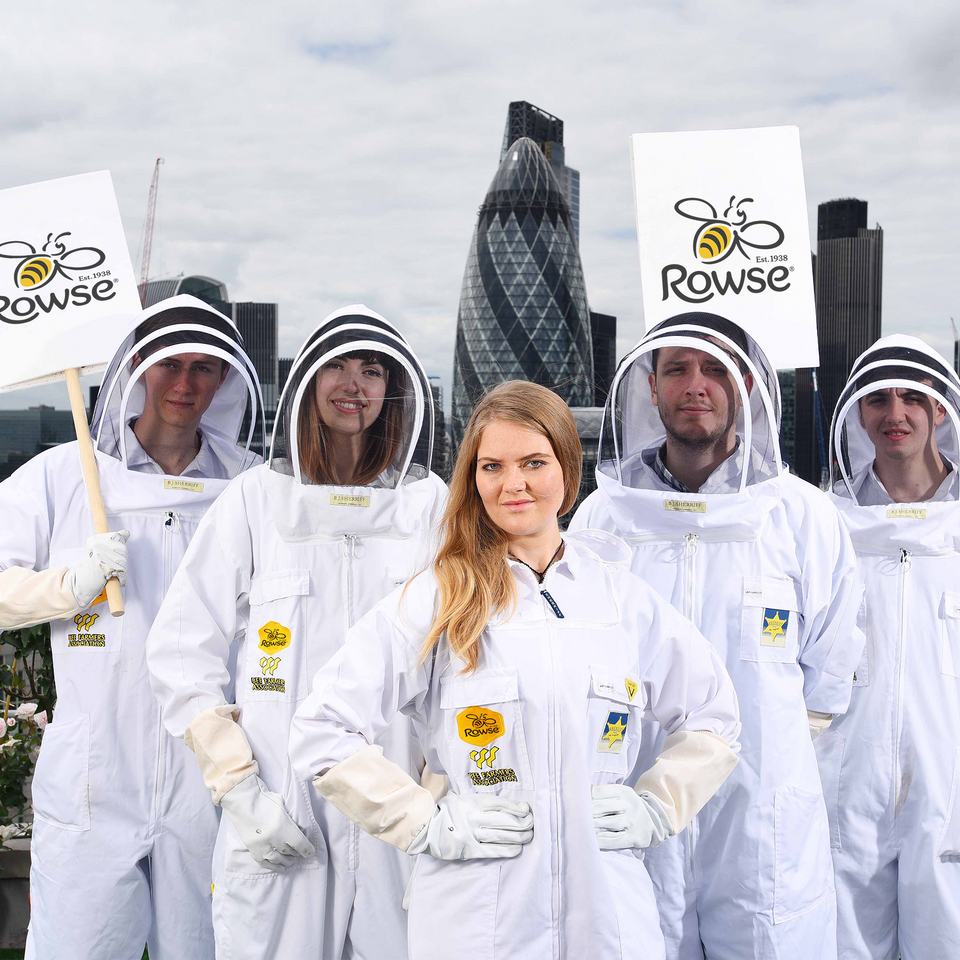 a group of people in beekeeper suits holding signs that say Rowse