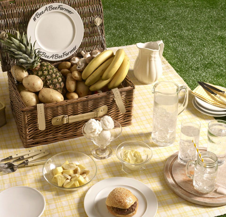 there is a picnic basket filled with fruit and vegetables on the grass .