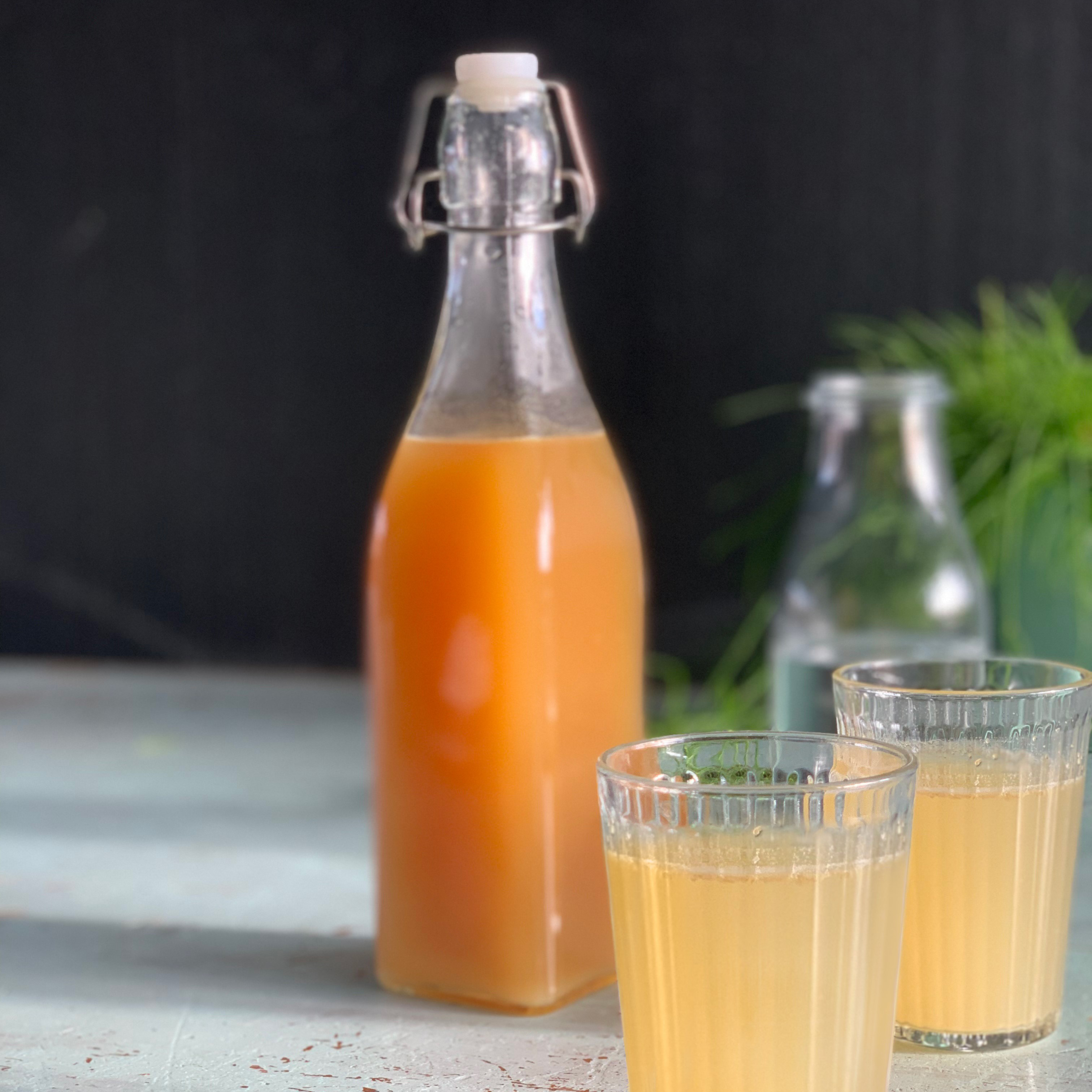 two glasses and a bottle of liquid on a table