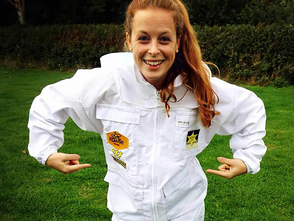 a woman wearing a bee suit has a patch on her chest that says bee hive