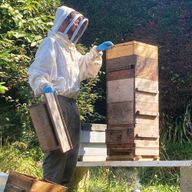 a man wearing a beekeeper 's suit is working on a beehive