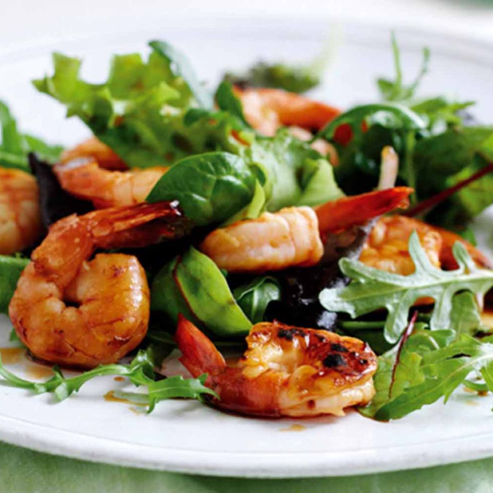 a white plate topped with shrimp , green peas , and lettuce .