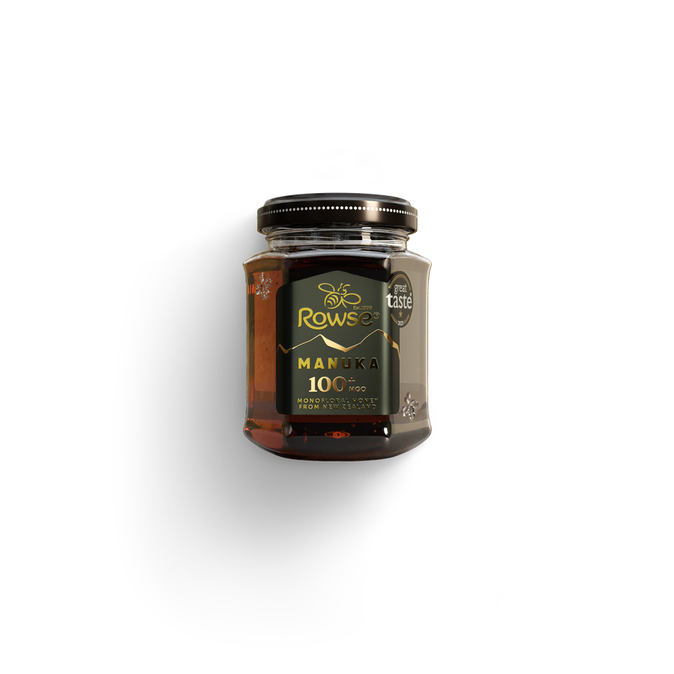 A dark glass jar of Rowse Manuka 100 MGO honey with a gold label and a "Great Taste" award sticker.