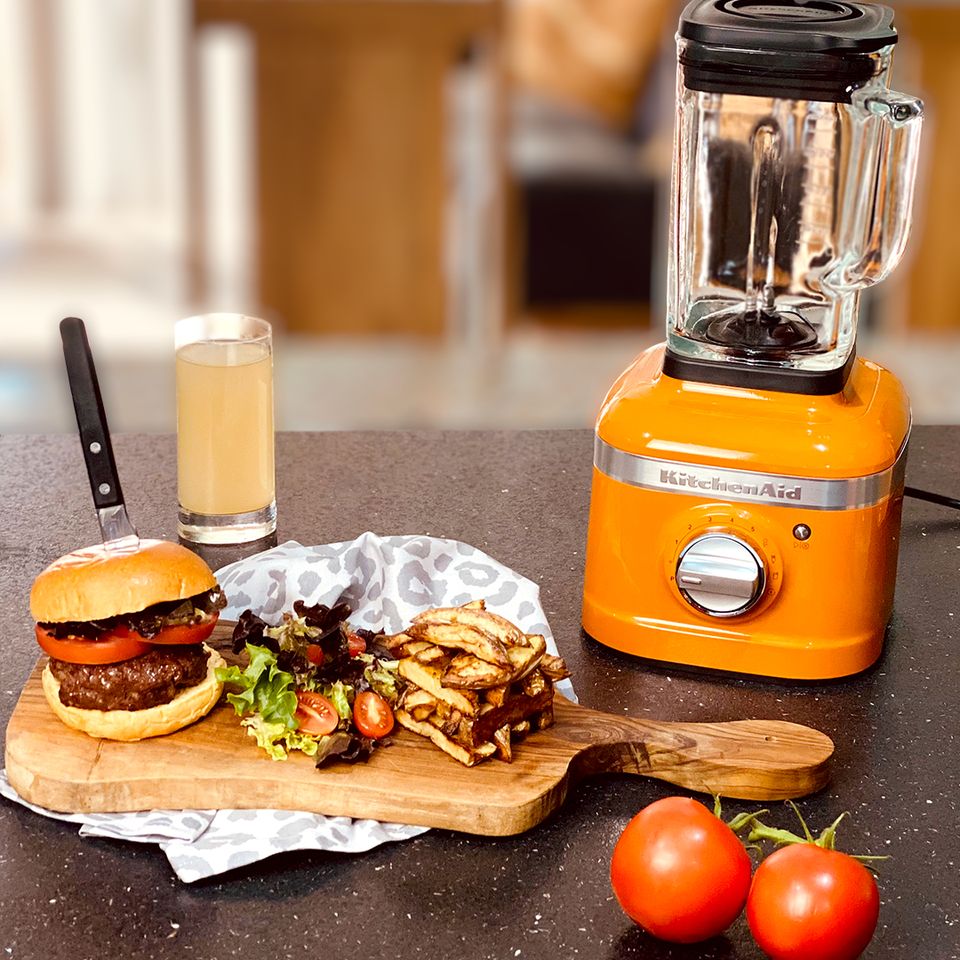 a blender is sitting on a counter next to a hamburger and french fries .