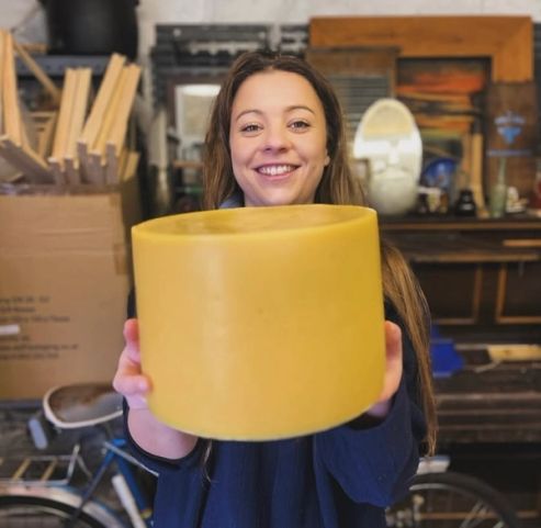 a woman is holding a large yellow cylinder in her hands and smiling .