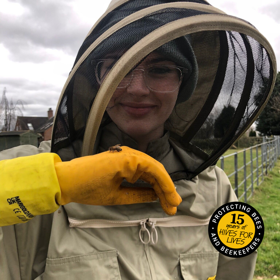 a woman wearing a bee suit holds a bee in her hand