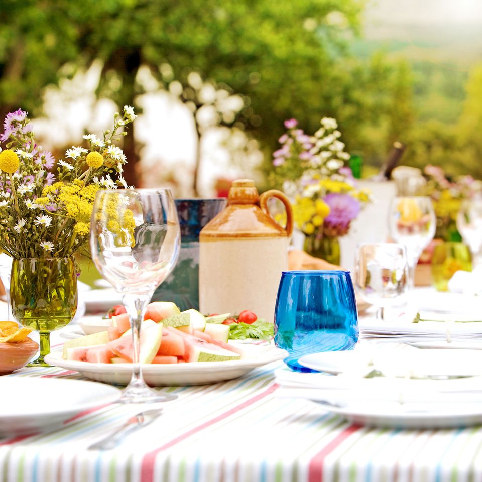 a long table with plates , glasses , and flowers on it .