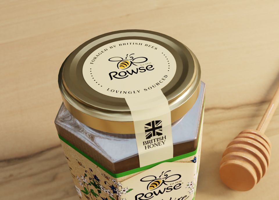 A jar of Rowse honey next to a wooden honey dipper.