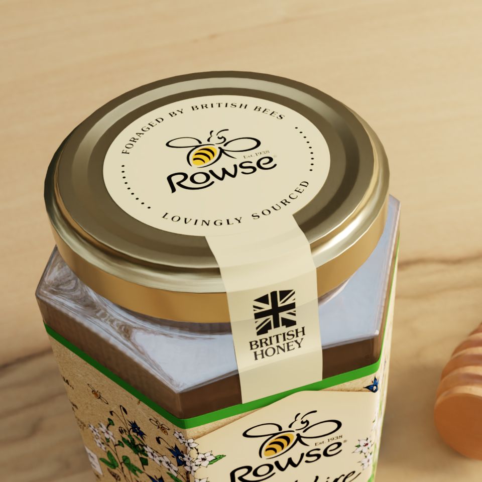 a jar of honey is sitting on a wooden table next to a honey dipper .