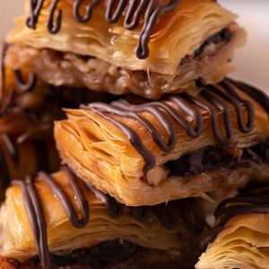 a close up of a stack of baklava covered in chocolate .