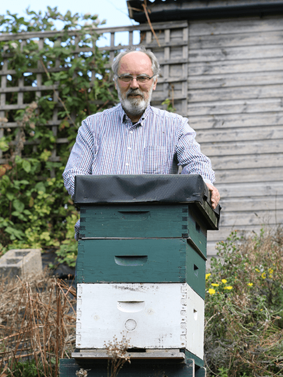 a man standing next to a beehive that has the letter e on it