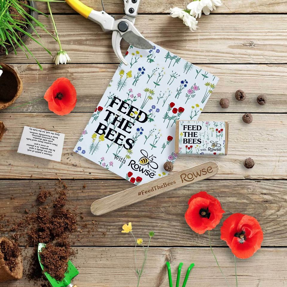 a wooden table topped with flowers , seeds , and gardening tools .