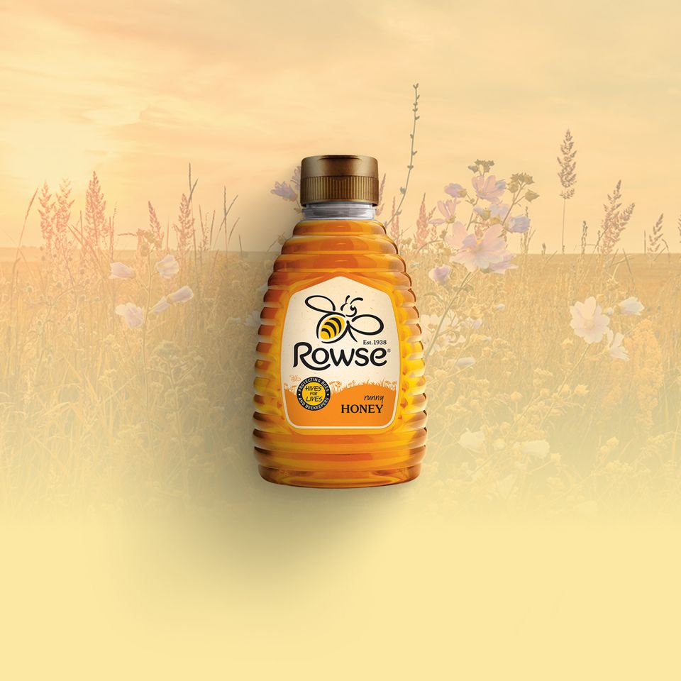 a bottle of Rowse Honey in front of a field of flowers .