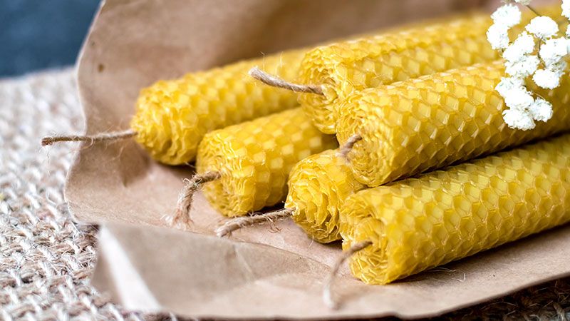 a bunch of beeswax candles are stacked on top of each other on a piece of brown paper .