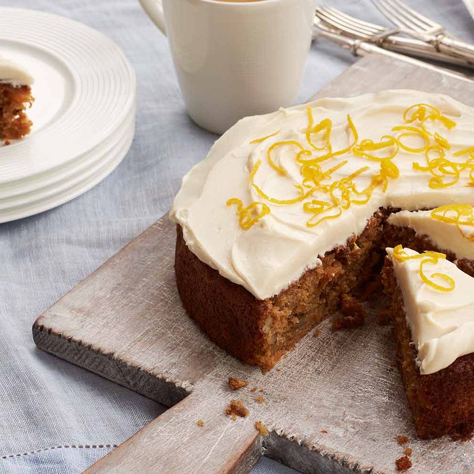 a carrot cake with a slice taken out of it is on a cutting board .