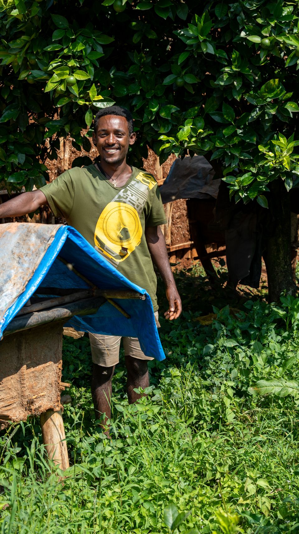 a man is standing next to a beehive in a field .