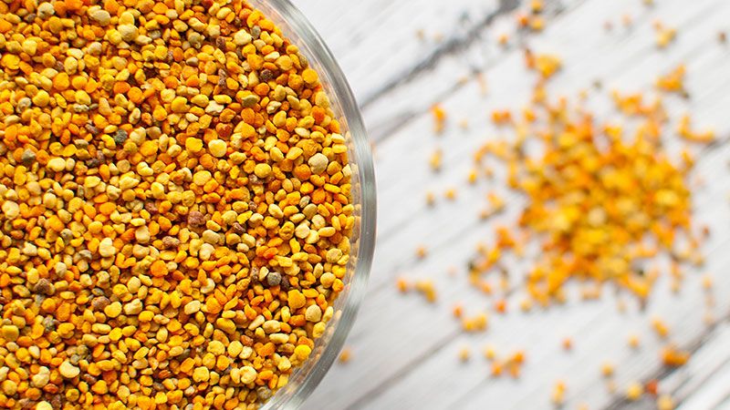a glass bowl filled with bee pollen on a wooden table .